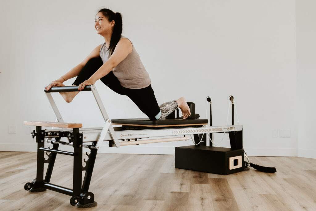 A smiling client in a lunge on the Pilates Reformer